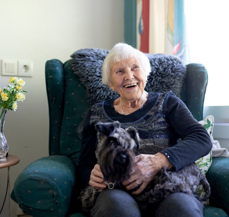 Beboer koser seg med en hund på fanget i en behagelig stol